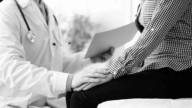 Lege sitter sammen med pasient og holder hånden hennes mens han gjennomgår dokumenter.